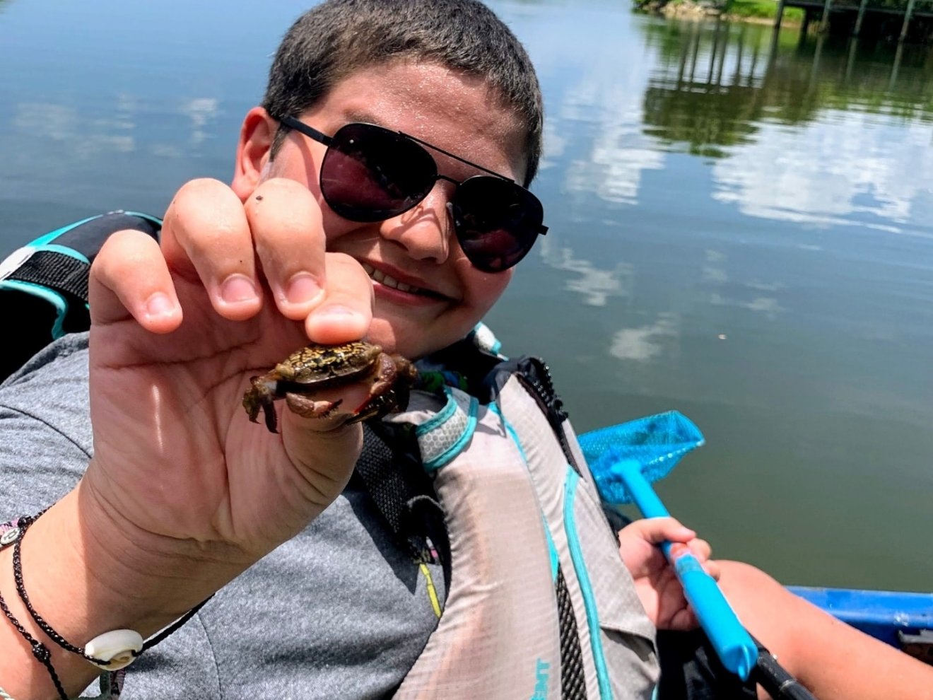 a person wearing sunglasses drinking from a lake