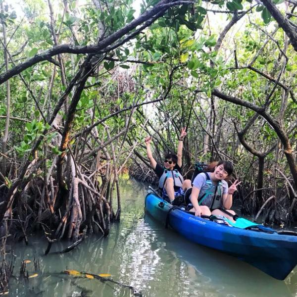a group of people on a boat in the water next to a tree