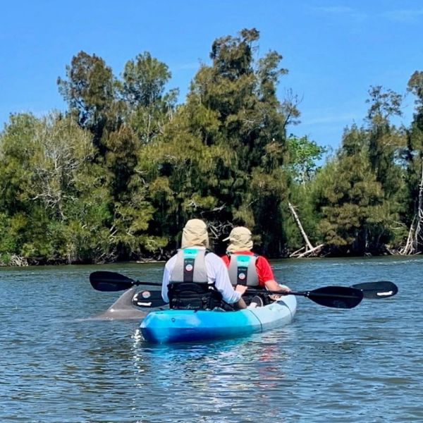 a man riding on the back of a boat next to a lake