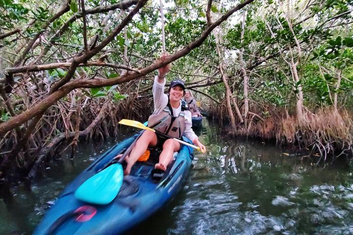a man riding on the back of a boat next to a river