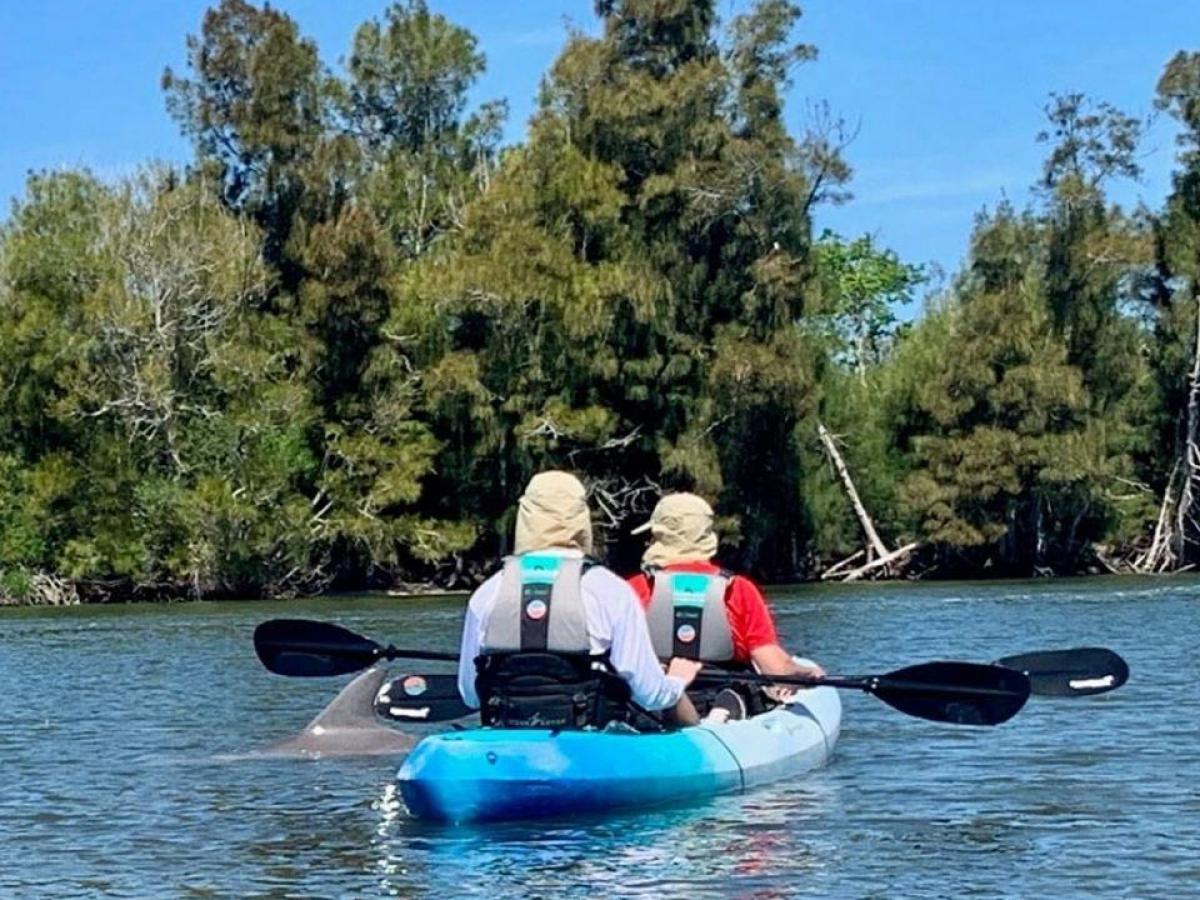 a man riding on the back of a boat next to a lake