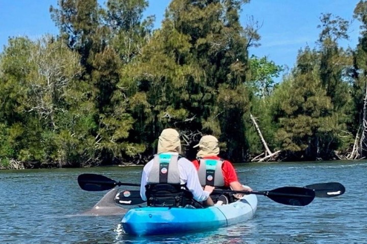 a man riding on the back of a boat next to a lake