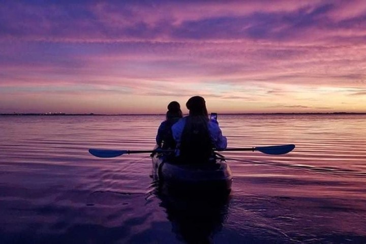 a person standing in front of a sunset over a body of water