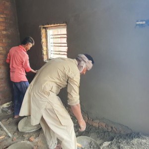 a man standing next to a brick wall
