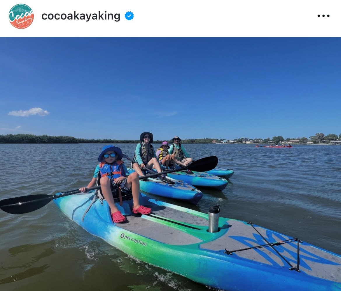 Group of people kayaking on calm water under clear blue sky.